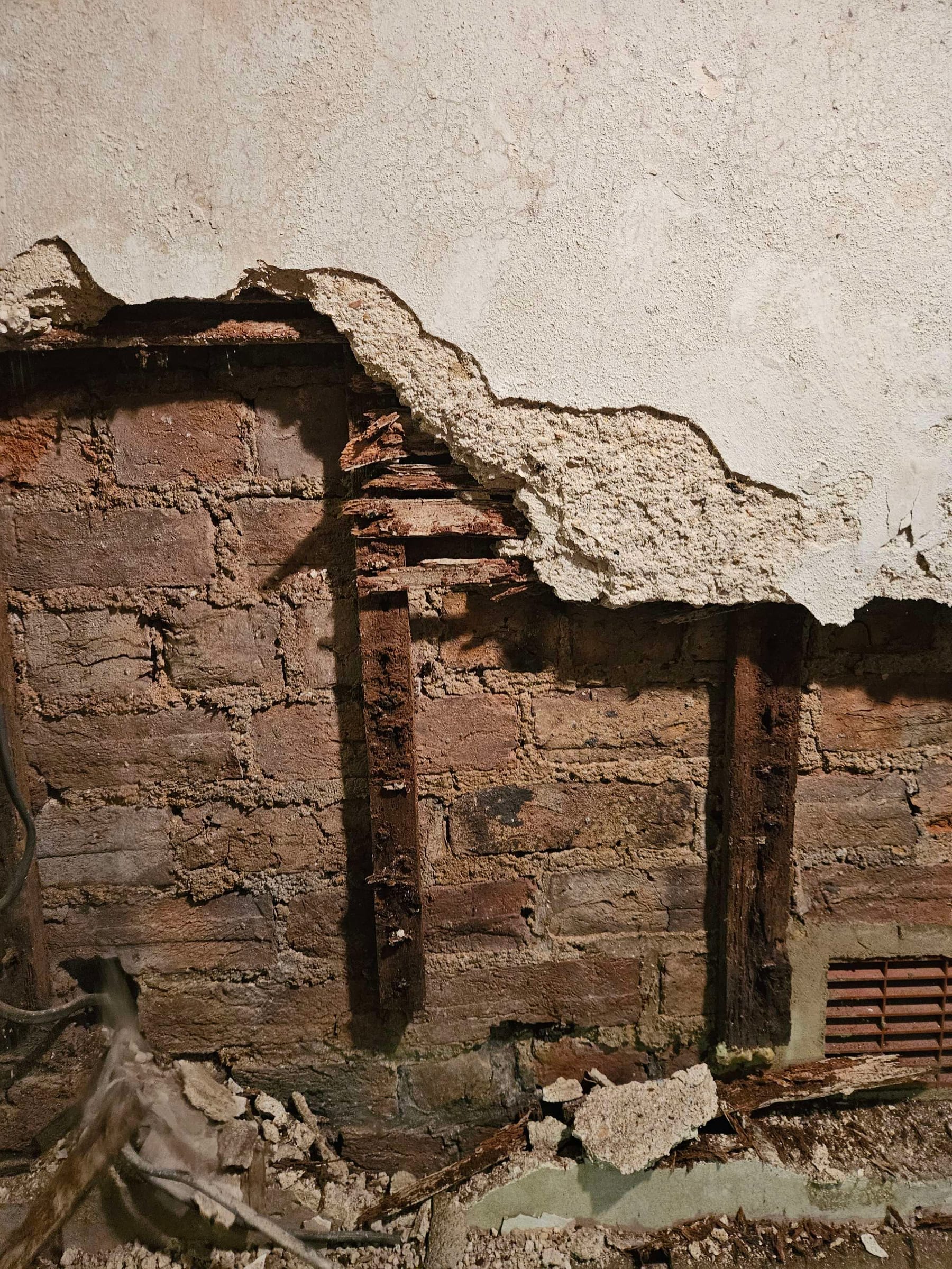 Failed lath and plaster exposing the timber and brick behind