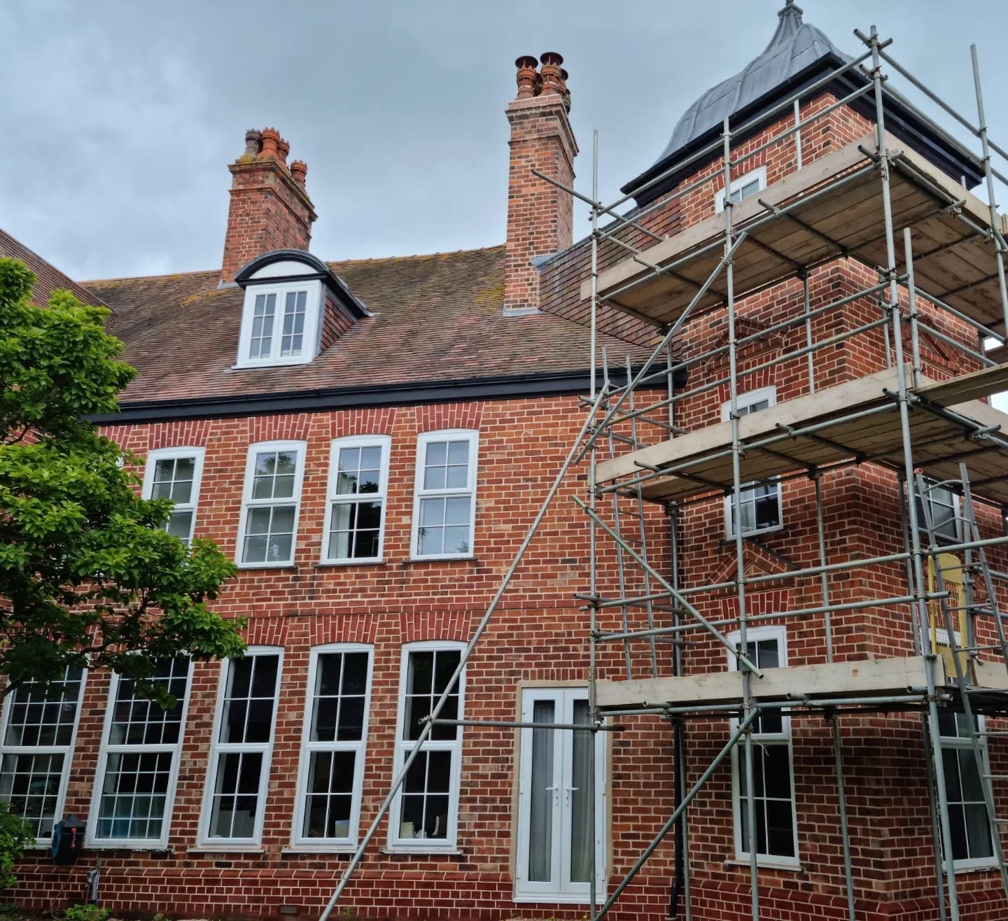 Large red brick house under scaffold during masonry restoration, Woodhall