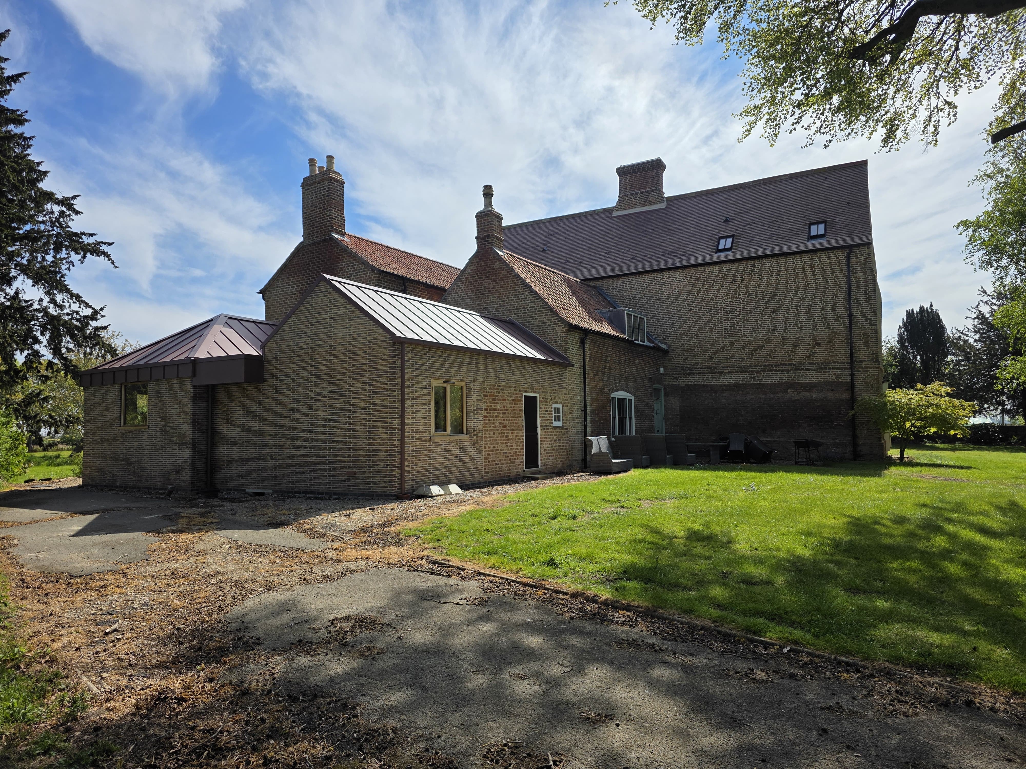 Stone house with a new single-storey extension under a standing-seam metal roof, Donington