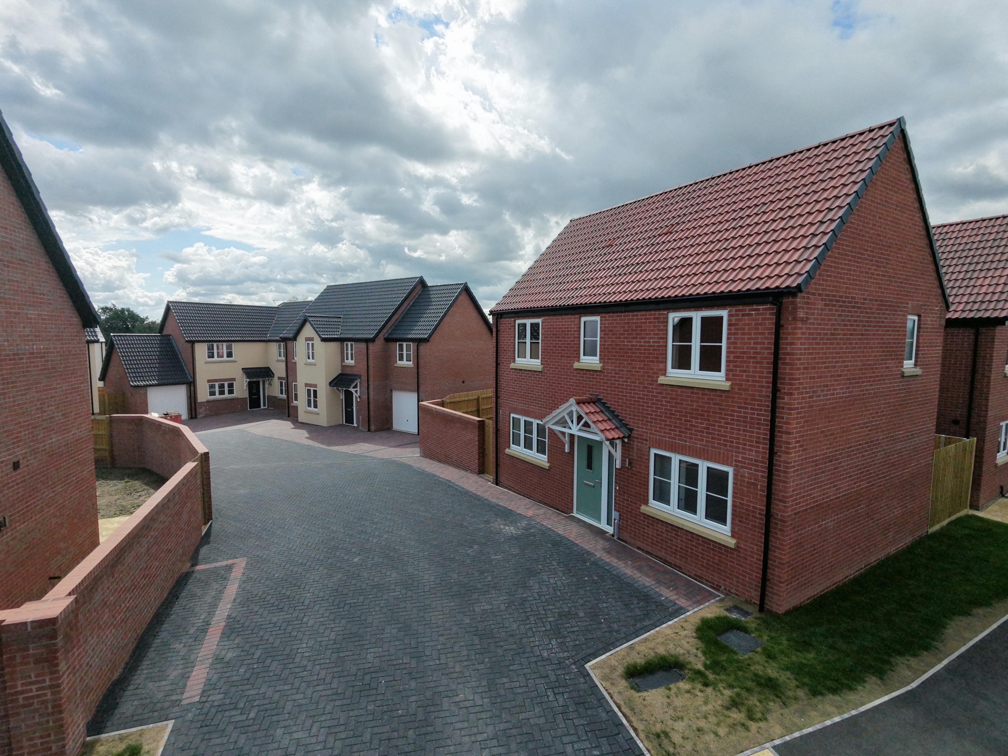 Finished new-build houses in red brick along a completed street, part of a new-build masonry package in Bardney